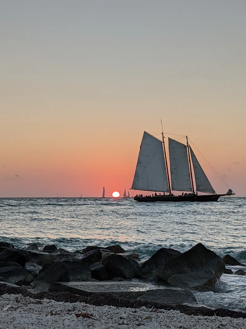 The original photo: a sailboat off a rocky shore at sunset